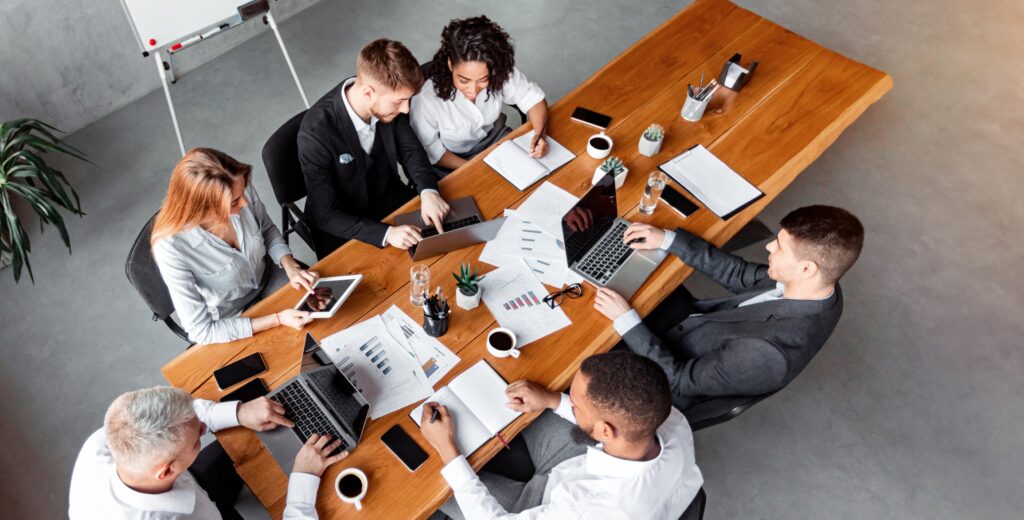 Colleagues Talking Sitting With Gadgets During Meeting In Office, High-Angle