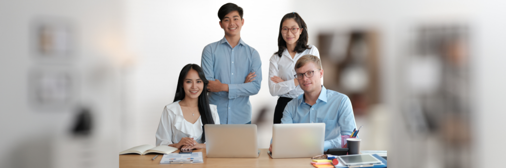 Equipo de profesionales trabajando con ordenadores portátiles en un entorno de oficina moderno y colaborativo.